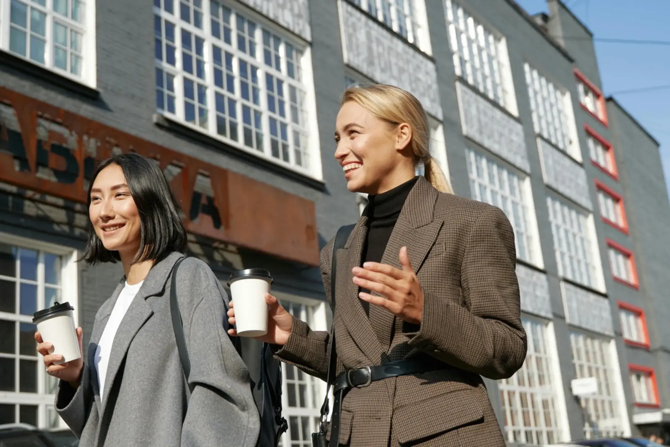 two woman walking holding a coffee
